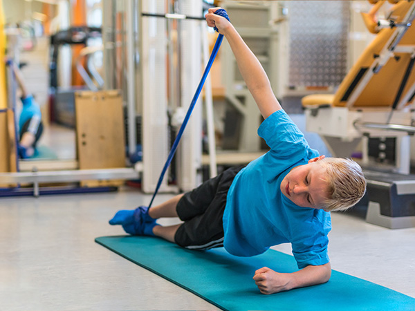 Junge macht Übungen mit Theraband